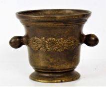 A 19th century bronze mortar the body decorated with a floral motif and with a pair of handles