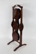 An Edwardian mahogany "Monoplane" folding cake stand, with a arched handle above five circular