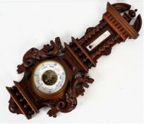 A 20th century mahogany cased barometer, with a carved mahogany case set with a pair of carved