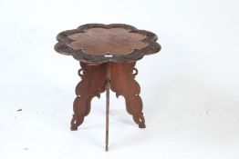 An Anglo Indian side table, the top decorated with a carved floral decoration raised on four legs,
