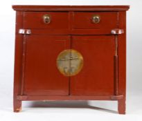 19th century Chinese red lacquered side cupboard, the plank top above two small drawers and pair
