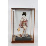 Japanese Geisha doll, 20th century, housed in a wooden and glazed case, 55cm tall, 36cm wide, 30cm