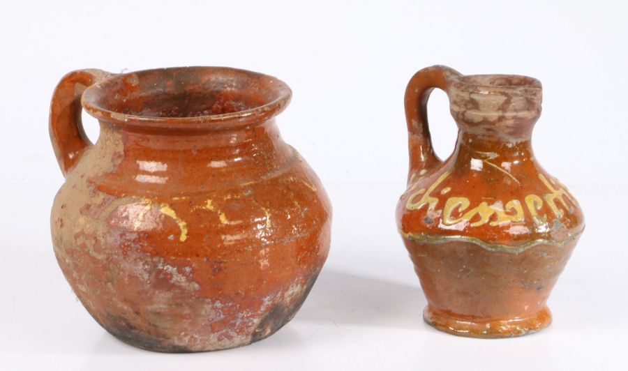 Two 17th century Dutch slipware pieces of pottery To include a jug with text to the bulbous body,