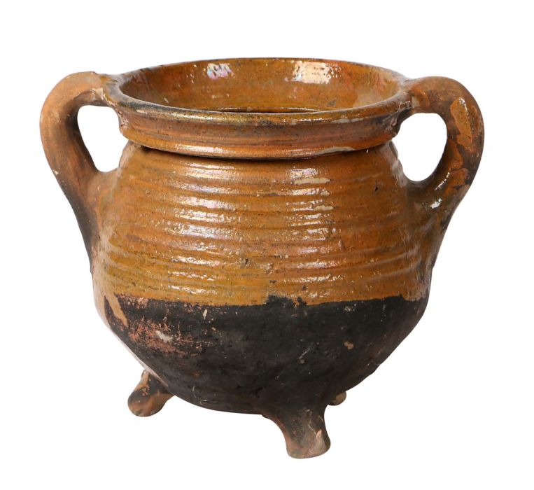 A 17th century Dutch pottery cauldron With a ribbed body and loop handles, on three dumpy feet, 20cm