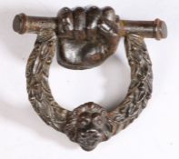 A 19th century cast iron door knocker, circa 1820 Designed as a clenched fist holding a bar, with
