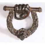 A 19th century cast iron door knocker, circa 1820 Designed as a clenched fist holding a bar, with