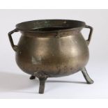 A 16th century bronze cauldron The bulbous body with flared lip and angular handles, on tripod feet,