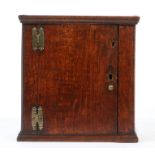 A small oak boarded mural cupboard, English, circa 1700 Having a simple cornice, plain door and