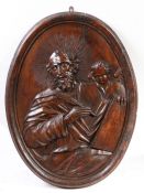 A large 17th century ‘limewood’ carved oval panel of  St Matthew and the Angel, circa 1650-1700