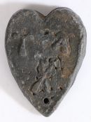 A lead trade weight, probably medieval, English Of heart-shape, with crossed implements, and the
