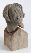 A late Medieval carved stone head Modelled as a wavy haired male with contorted mouth, on a later