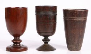 Three treen drinking vessels To include a ring-turned goblet, 17cm high, a turned goblet, 16.5cm
