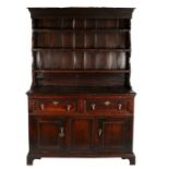 A George II oak enclosed high dresser, circa 1740 Having a slender boarded rack, with three shelves,