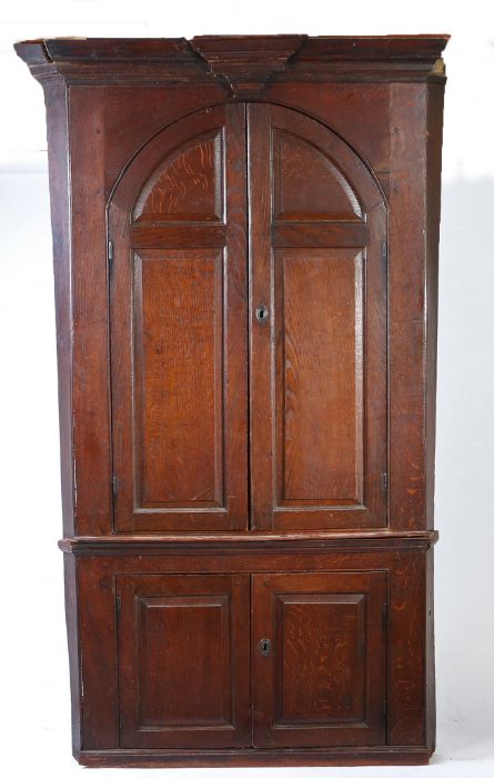 An oak barrel-back standing corner cupboard, circa 1800 The bold moulded cornice with key-stone,