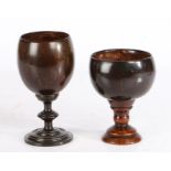 Two treen coconut cups Each with a turned stem and base, 11cm high and 14cm high, (2)