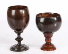 Two treen coconut cups Each with a turned stem and base, 11cm high and 14cm high, (2)
