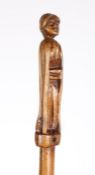 An 18th century treen baton The terminal carved as female figure with crossed arms, 50cm long