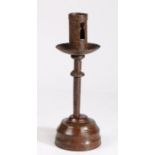 A 16th century iron socket candlestick, on an early 19th century lignum vitae base  Having a