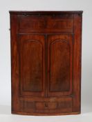 George III mahogany bow front hanging corner cupboard, having crossbanded frieze above a pair of