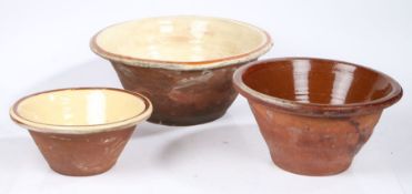 Two slip ware bowls, each with glazed interiors with a brown band to the rim, and one other bowl,