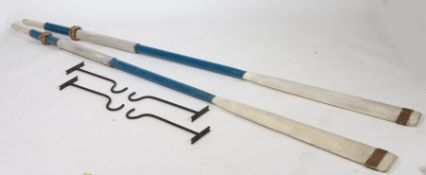 Pair of painted wooden oars, painted in blue and white, each with a copper band to one end, with