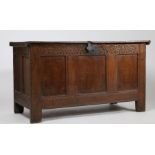 An 18th Century oak coffer, the hinged lid above an arched carved frieze and triple panelled