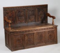 19th century oak settle, the back rest with carved diamond lozenge and foliate panels, with hinged