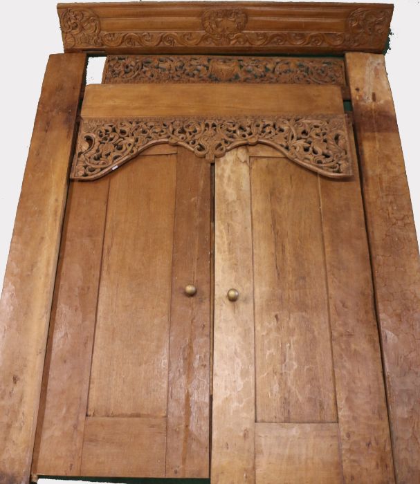 A pair of substantial Indonesian doors and frame, the scroll, carved pediment above a pierced scroll