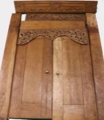 A pair of substantial Indonesian doors and frame, the scroll, carved pediment above a pierced scroll