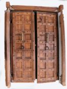 A pair of hardwood panelled doors, each door with fourteen panels, brass handle and iron hinges,