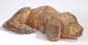 A carved dog, life size in a laying position, 74cm long