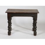 An oak occasional table, the rectangular top above a lunette carved frieze, raised on turned legs,