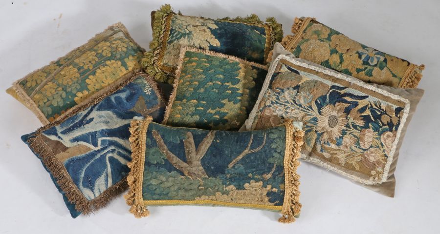 A collection of seven 17th/18th Century tapestry covered cushions, each in verdure patterns, some