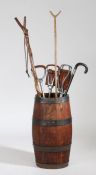 A barrel, of squat form, with a collection of shooting sticks and walking sticks, (7)