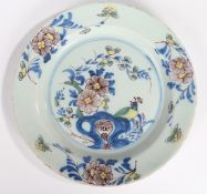 An 18th Century English Delft plate, with a bird seated on a stylised rock by flowers, 22cm diameter