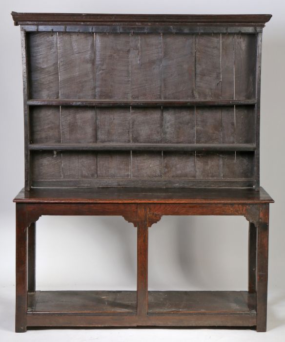 An 18th Century oak dresser and rack, the rack with a concave cornice above two shelves, the base