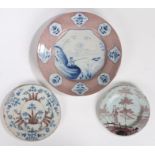 Three 18th Century English Delft plates, to include a manganese and blue painted charger with a