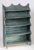 A pastel blue painted waterfall bookcase,  the arched gallery top above five waterfall shelves