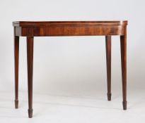 A George III mahogany and boxwood strung games table, the hinged bow fronted top above a boxwood