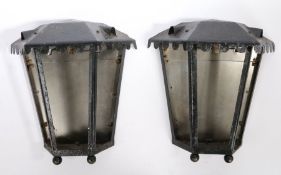 A pair of metal wall lamps, painted black with a frieze above an angled front, 42cm high, (2)
