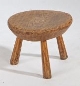 A 19th Century beech stool, the circular top above three angled chamfered legs, 27cm wide, 21.5cm