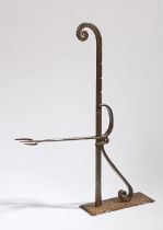 An 18th Century steel toasting fork, the adjustable fork arm on a notched rod and scroll mounts,