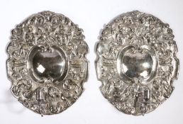 A pair of silvered wall lights/sconces In the Charles II manner, stamped TSC, with winged angels