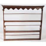 A late 18th Century oak plate rack, with a concave cornice above an undulating apron and three