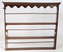 A late 18th Century oak plate rack, with a concave cornice above an undulating apron and three