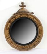 A Regency giltwood convex mirror, with a flaming final above a circular mirror plate and ball