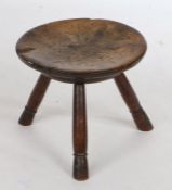 A 19th Century beech and ash stool, the circular dished top above three ring turned angled legs,