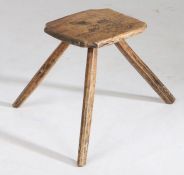 A 19th Century Welsh beech milking stool, the square top with inverted corners above three splayed