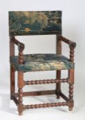 An 18th Century walnut armchair, the verdure tapestry pad back and seat flanked by bobbin turned