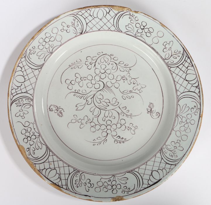 A mid 18th Century English Delft charger, circa 1760, with purple flower design to the centre and